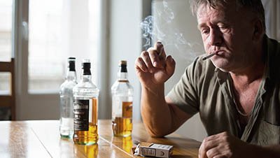 Вредные привычки Мужчина пьет сигарету и пьет алкоголь